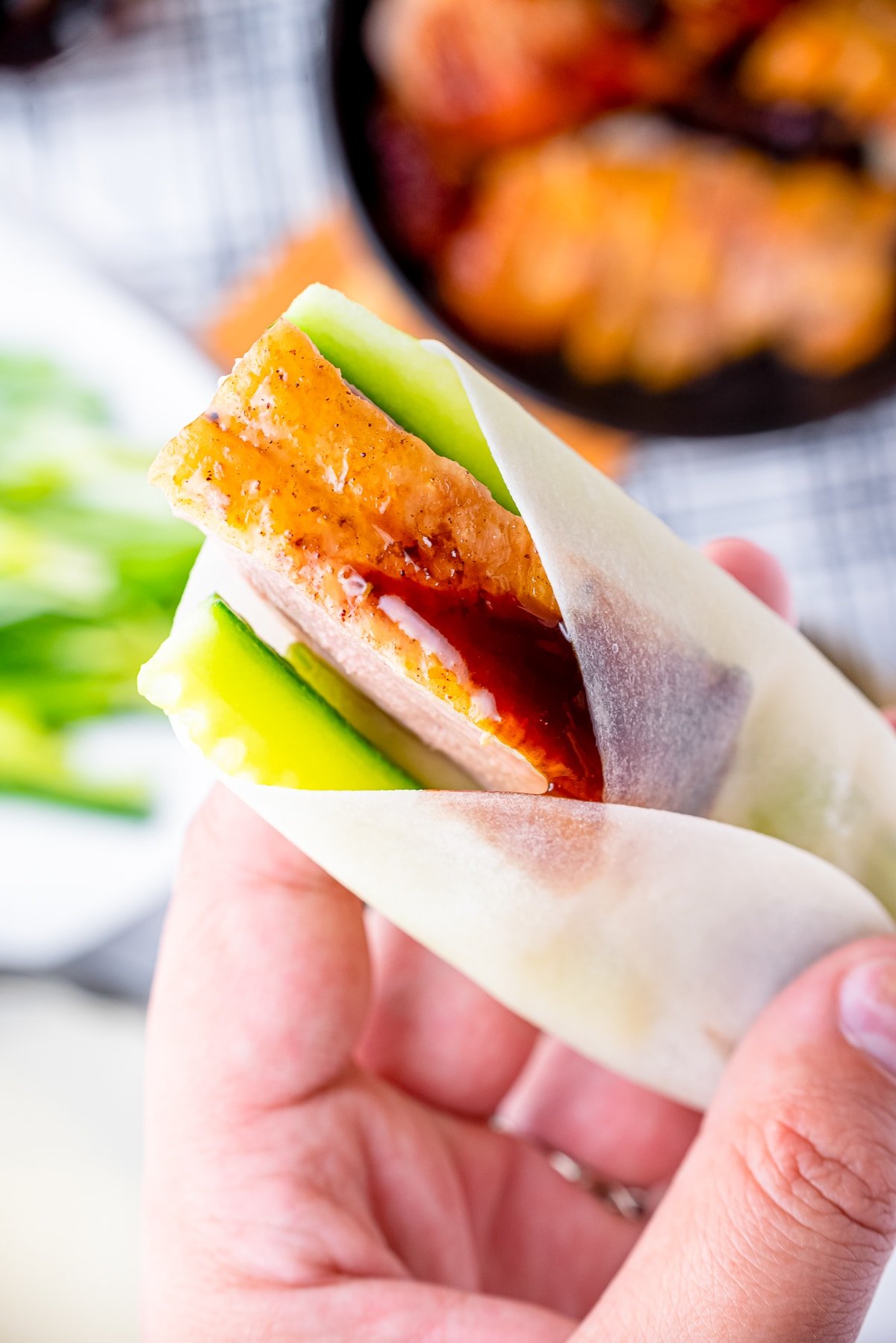 a hand holding up a best peking duck wrap in air
