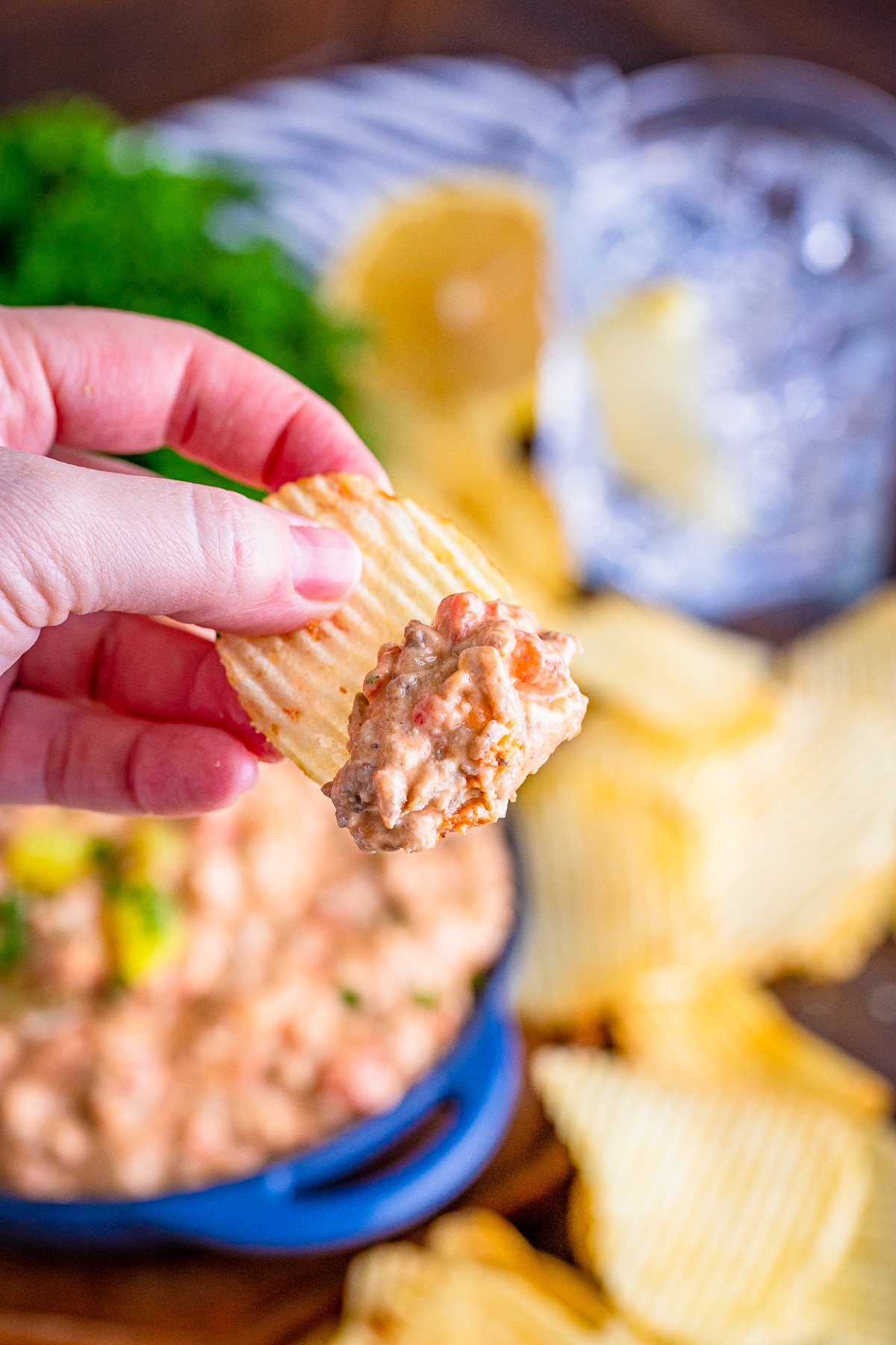 a hand holding up a chip that has cheeseburger dip on it