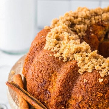 A whole snickerdoodle Bundt cake topped with cinnamon crumb topping on a cake stand.