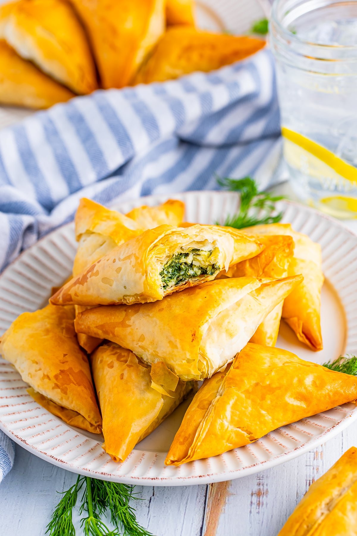 spanakopita triangles on a white plate with a bite taken out