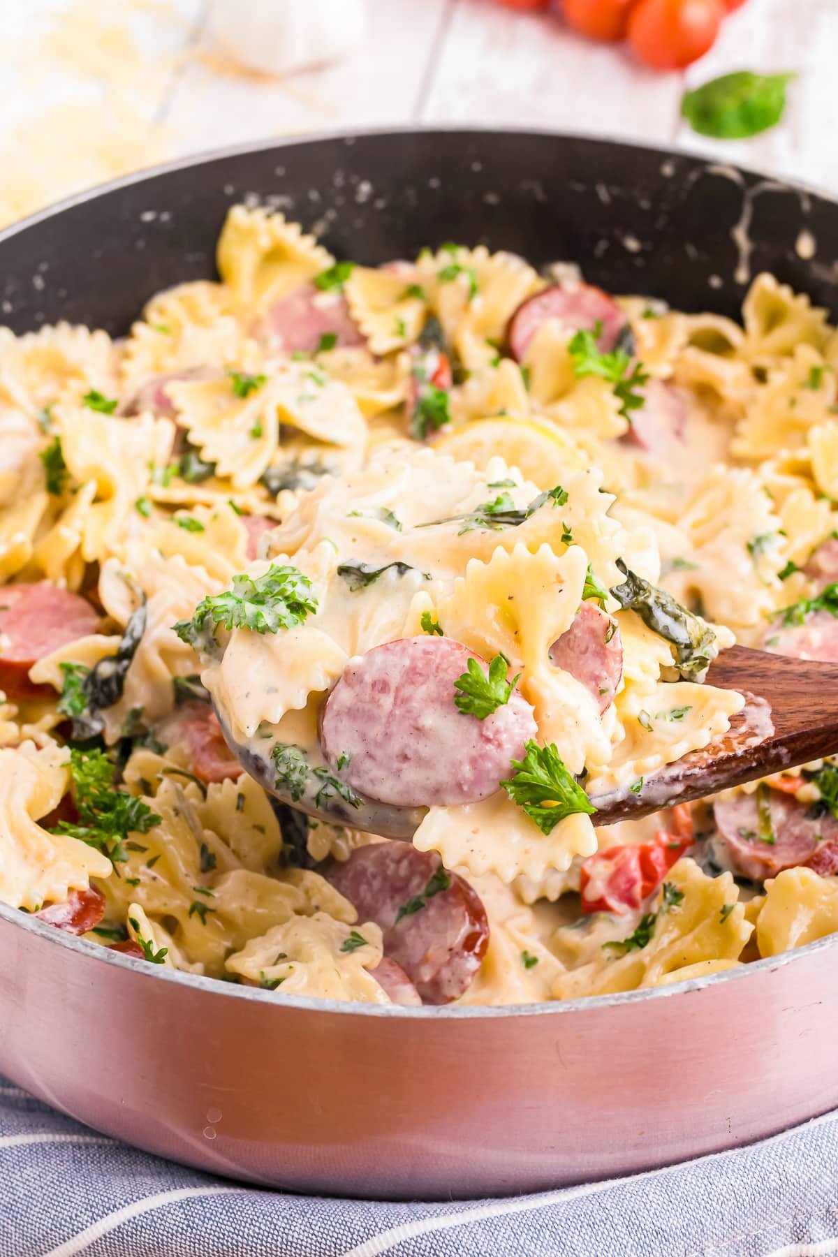 a spoon scooping out creamy sausage pasta from the pot