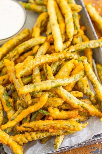 A platter of crispy beer battered fried green beans with a bowl of ranch.