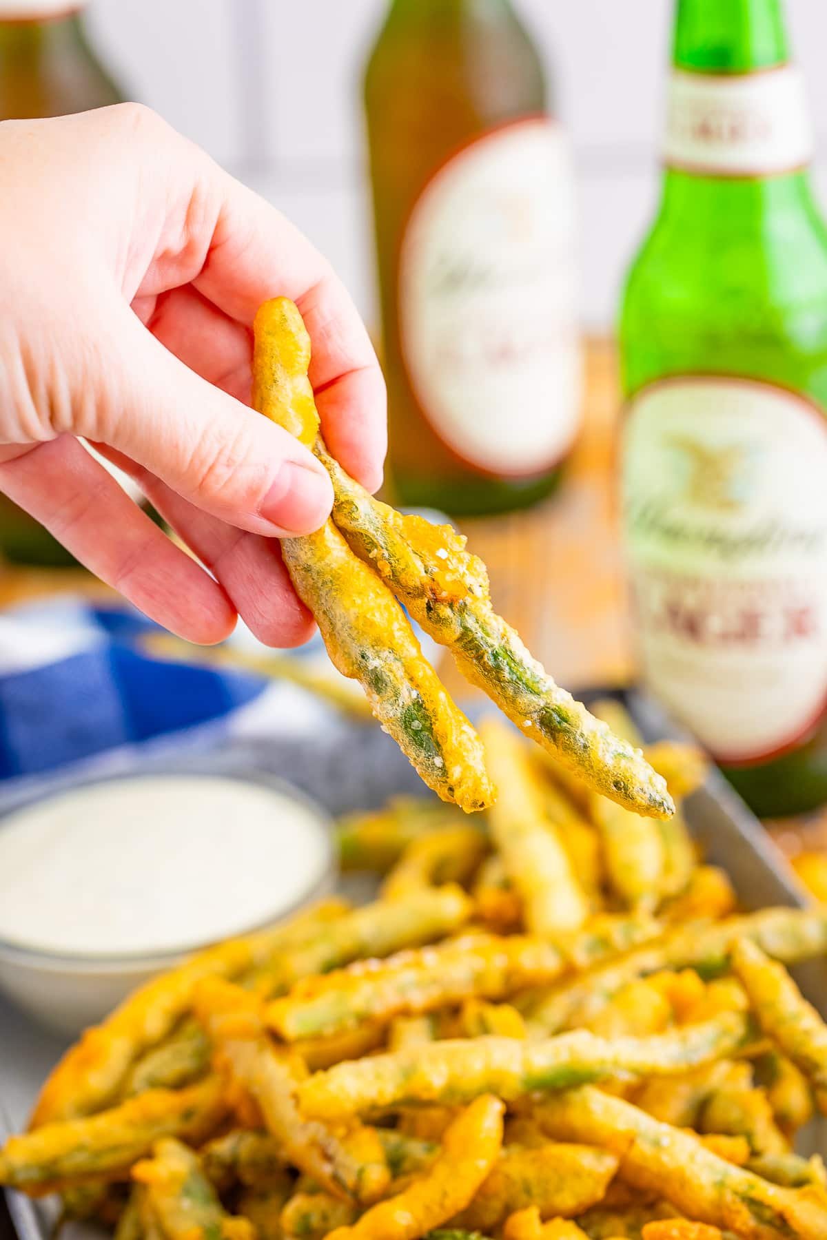 a hand holding fried green beans recipe in air