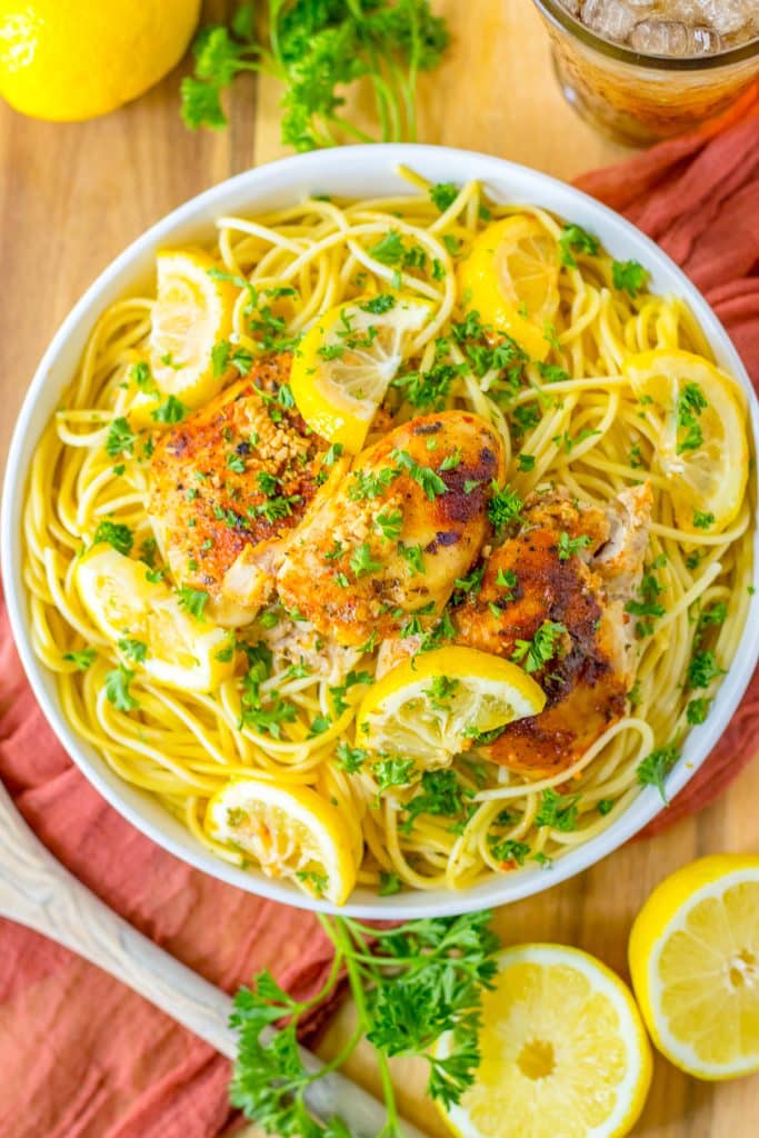 Slow cooker lemon chicken thighs in a white bowl with lemon slices and fresh parsley garnish.