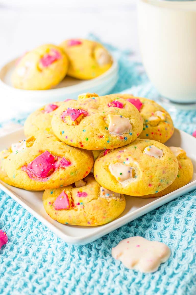 Thick and chewy animal cracker cookies on a white plate with a glass of milk.