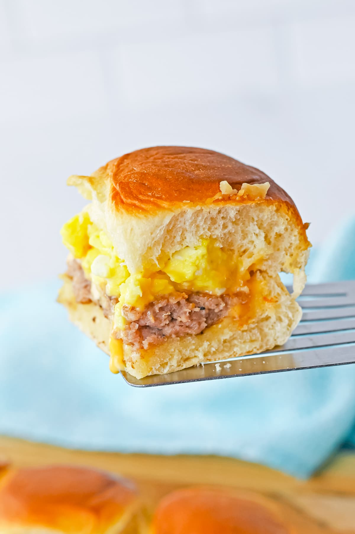 a spatula holding up breakfast sliders in air