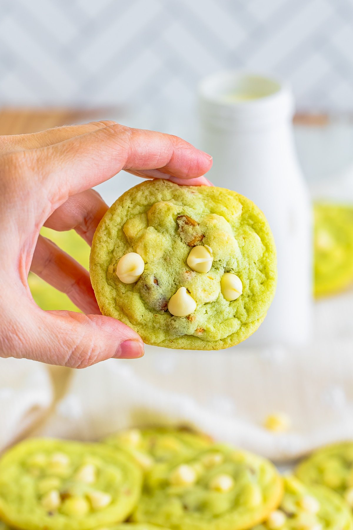 a hand holding up pistachio cookies in air 