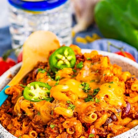 A bowl of cheesy chili mac topped with melted cheese and jalapeno slices.