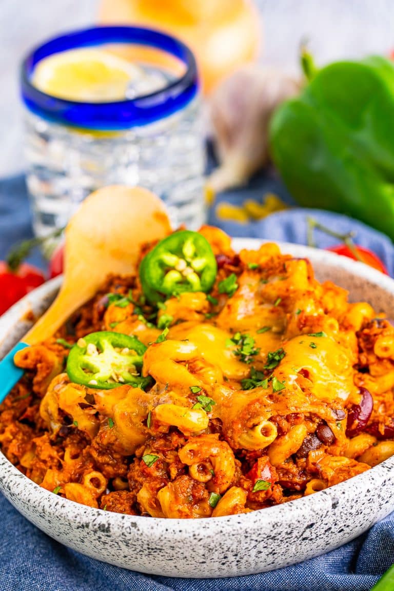 A bowl of cheesy chili mac topped with melted cheese and jalapeno slices.