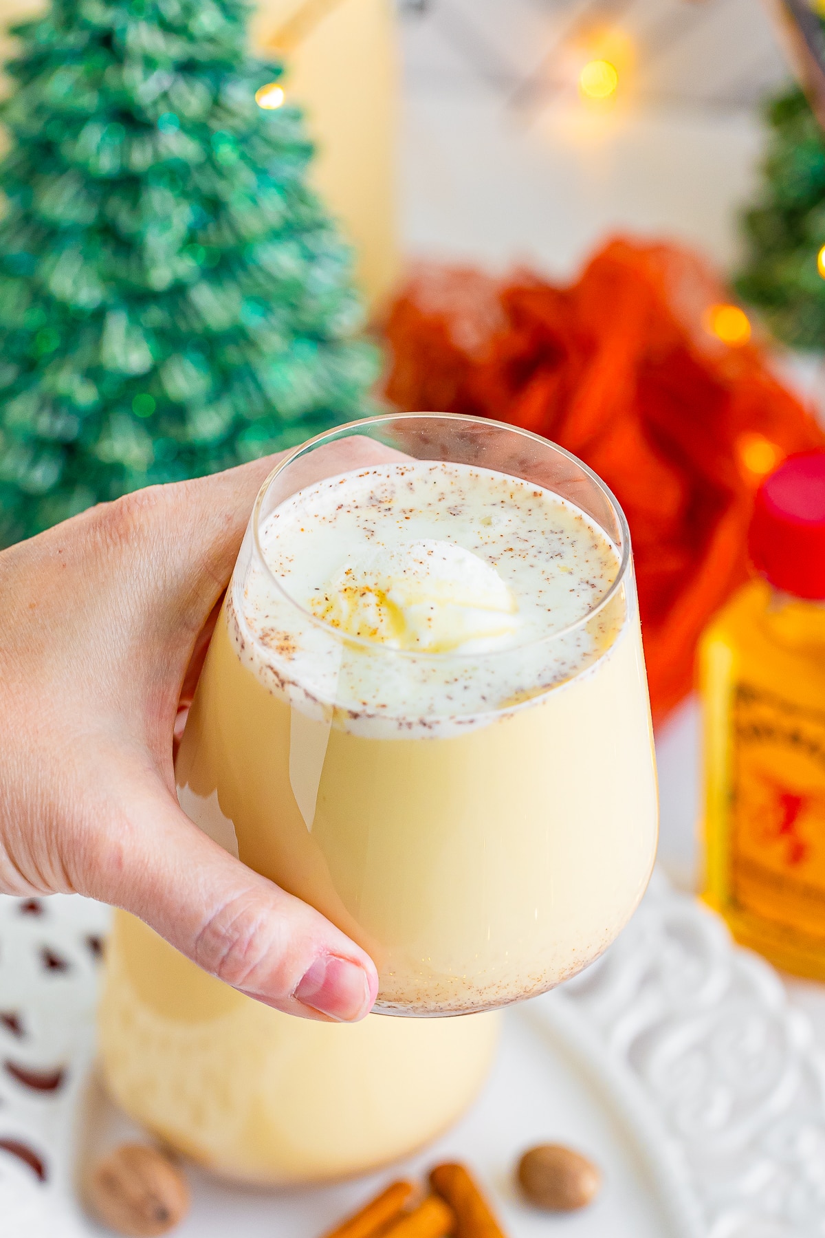 a hand holding up a glass full of christmas punch recipe in air