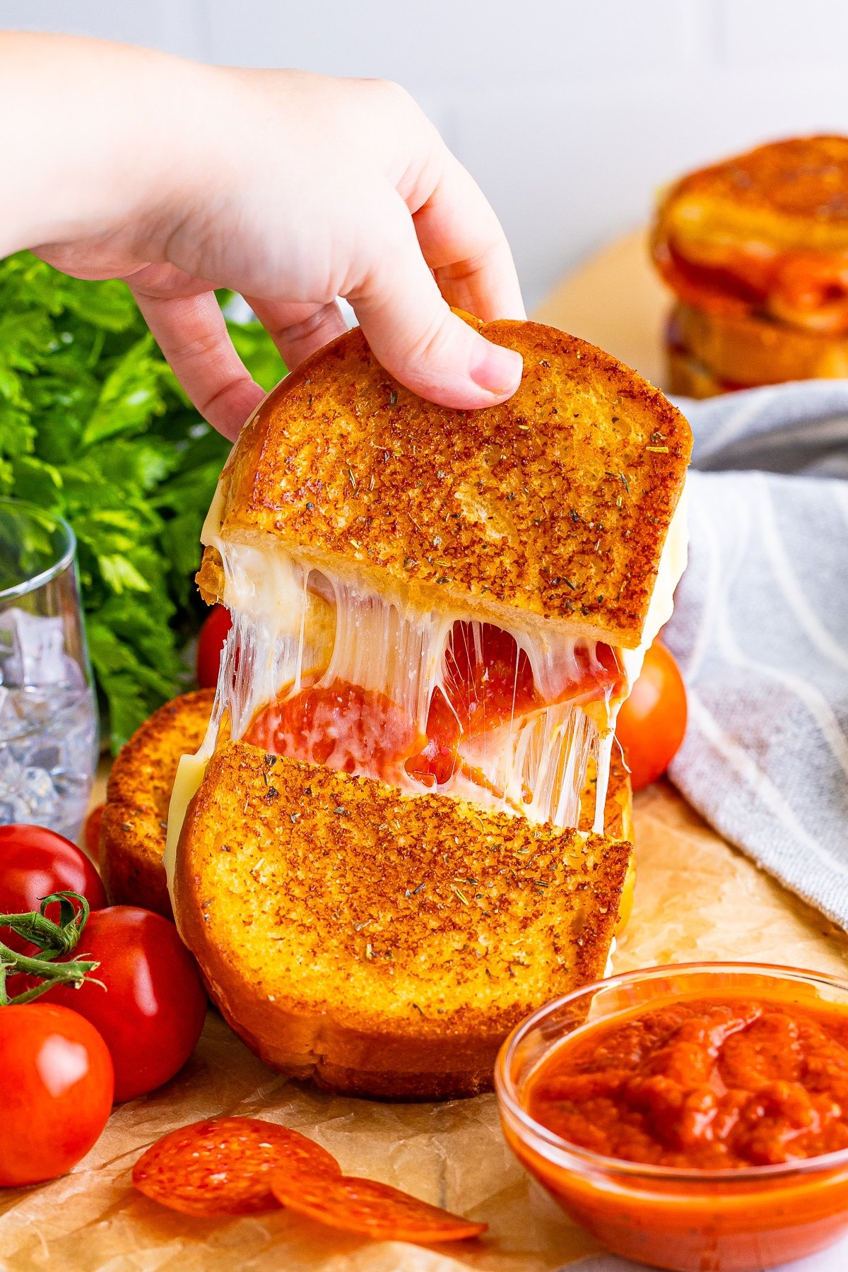 a hand pulling apart a pizza sandwich to show cheese pull