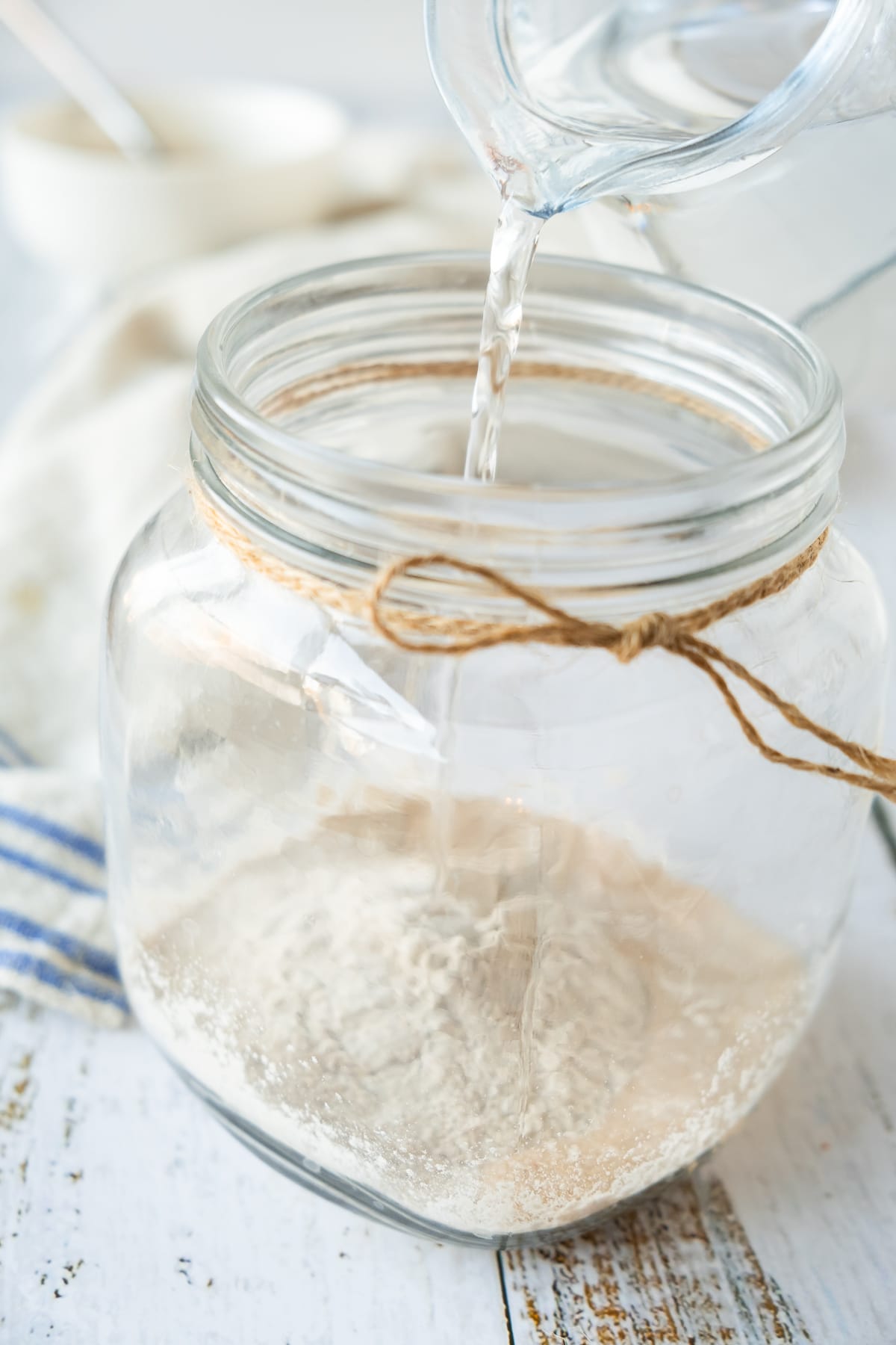 water being poured into jar for sourdough starter recipe