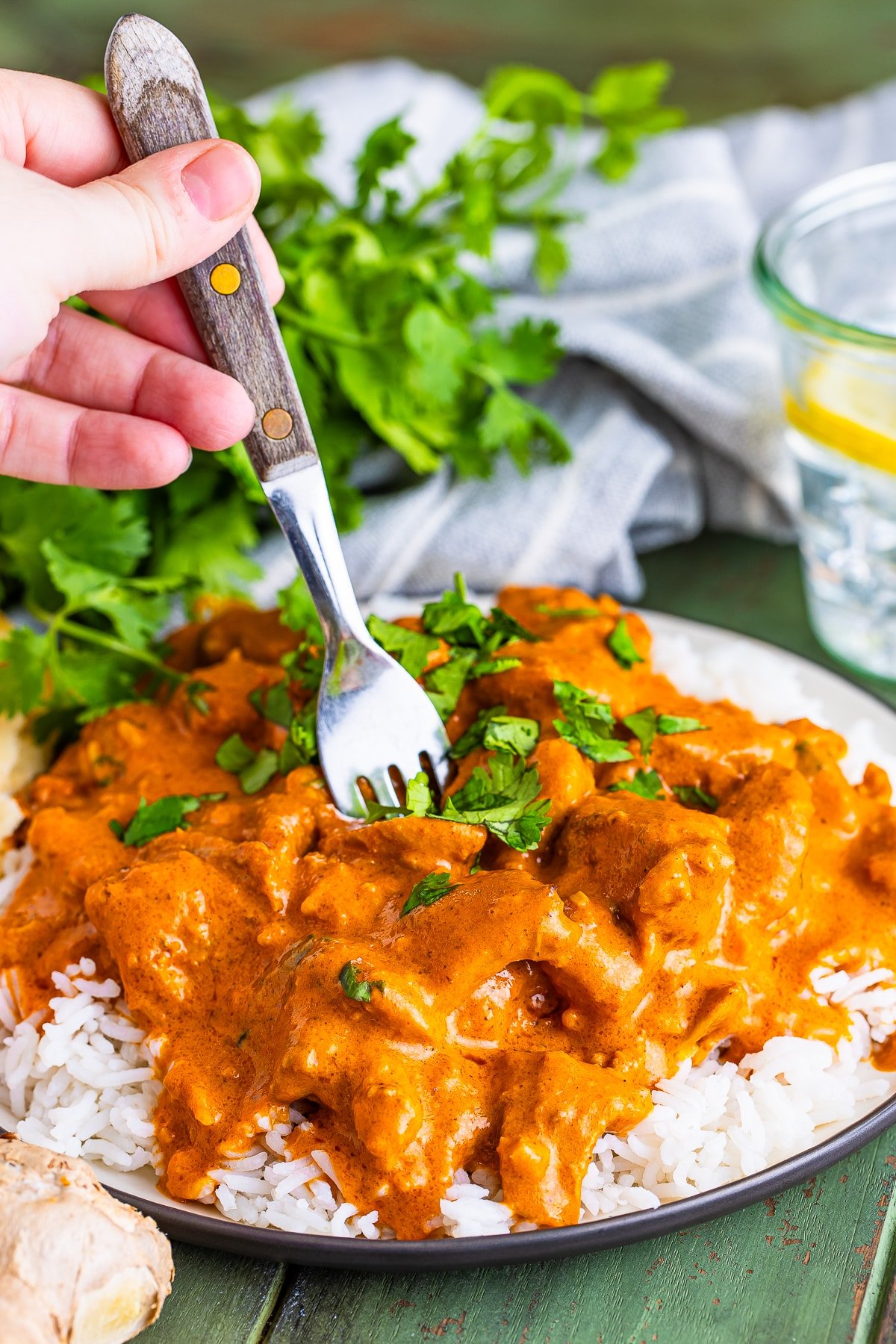 a fork digging into best butter chicken recipe on a tan plate