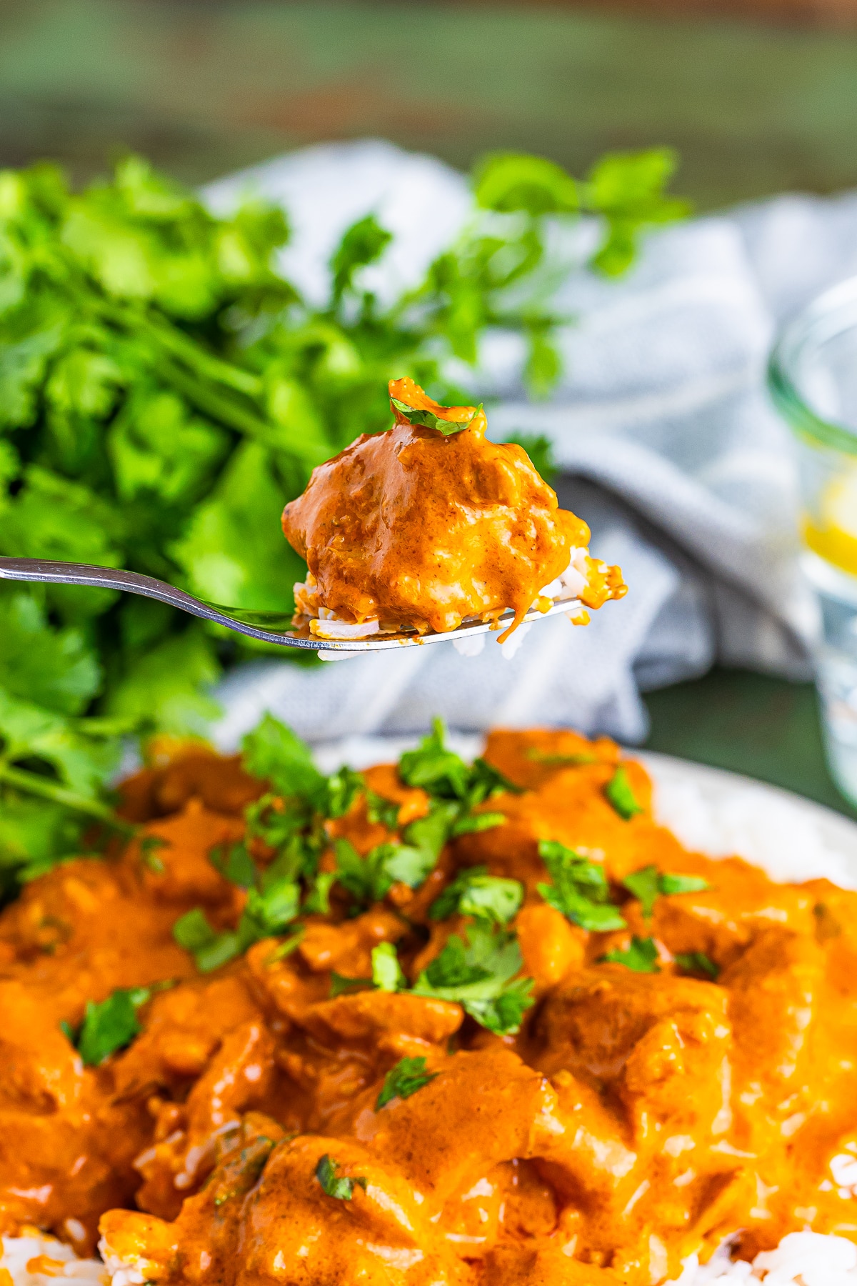 a fork holding up a bite of best butter chicken recipe in air