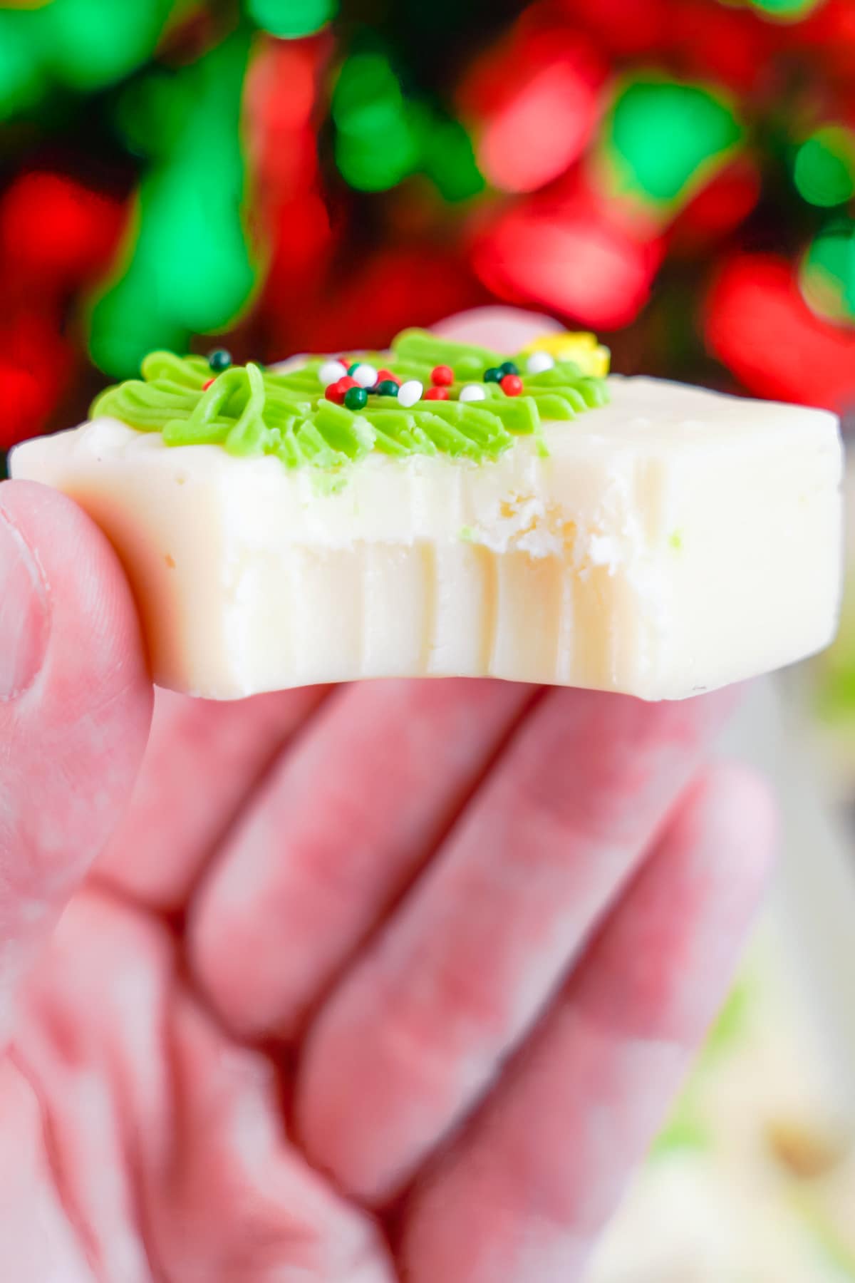 a hand holding up christmas fudge with a bite taken out