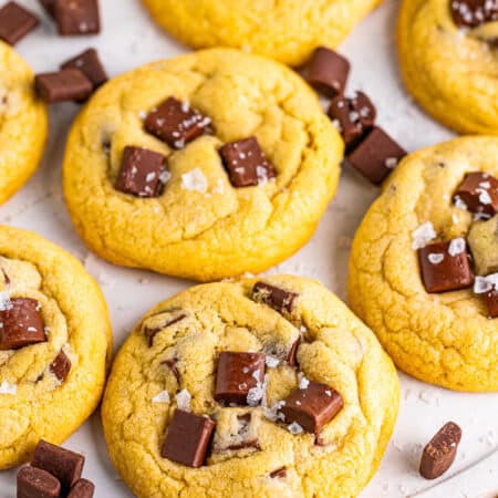 A stack of thick chocolate chunk cookies with melty chocolate chunks and flaky salt on top.