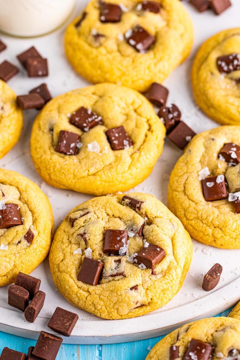 A stack of thick chocolate chunk cookies with melty chocolate chunks and flaky salt on top.