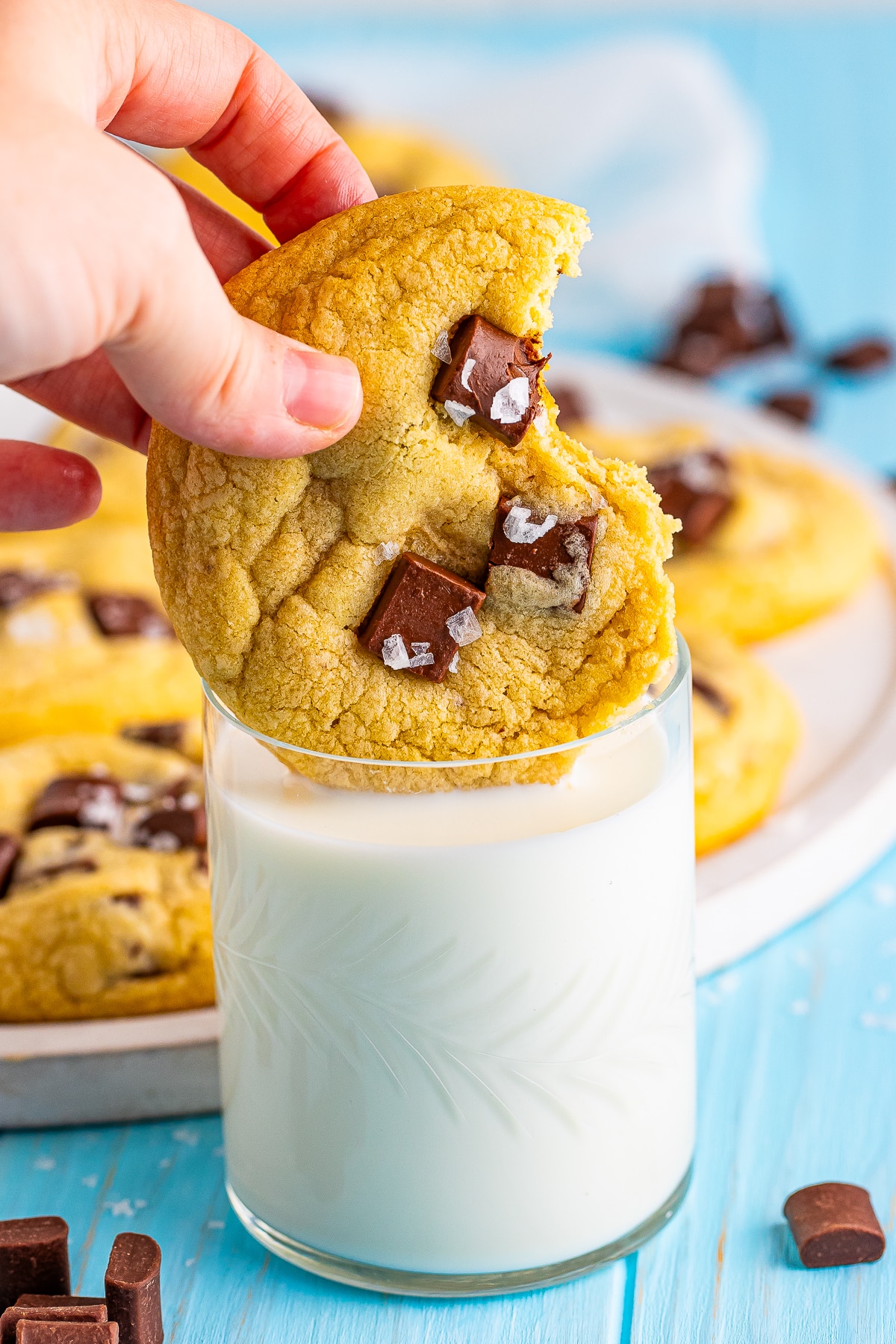 chocolate chunk cookies being dunked into milk