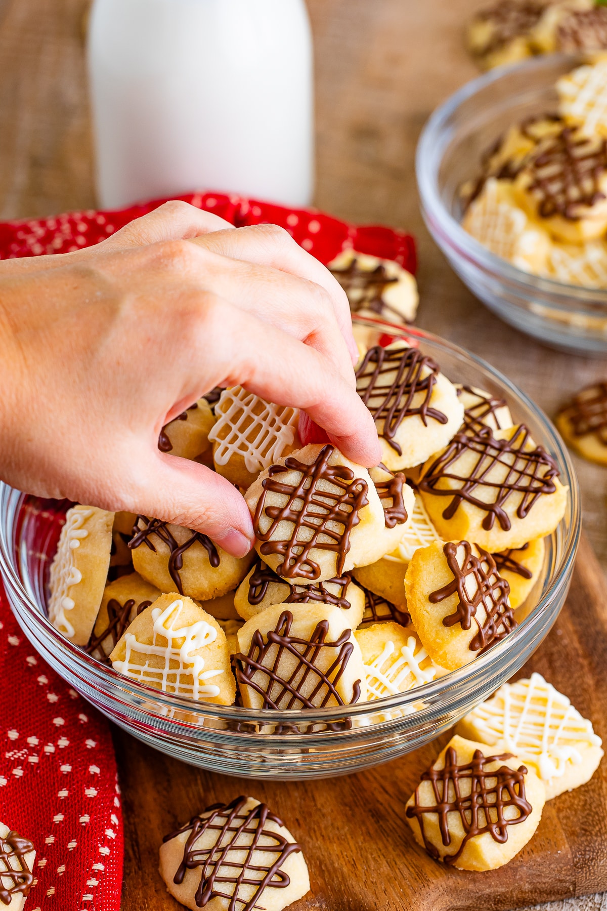 a hand grabbing christmas shortbread bite out of serving bowl