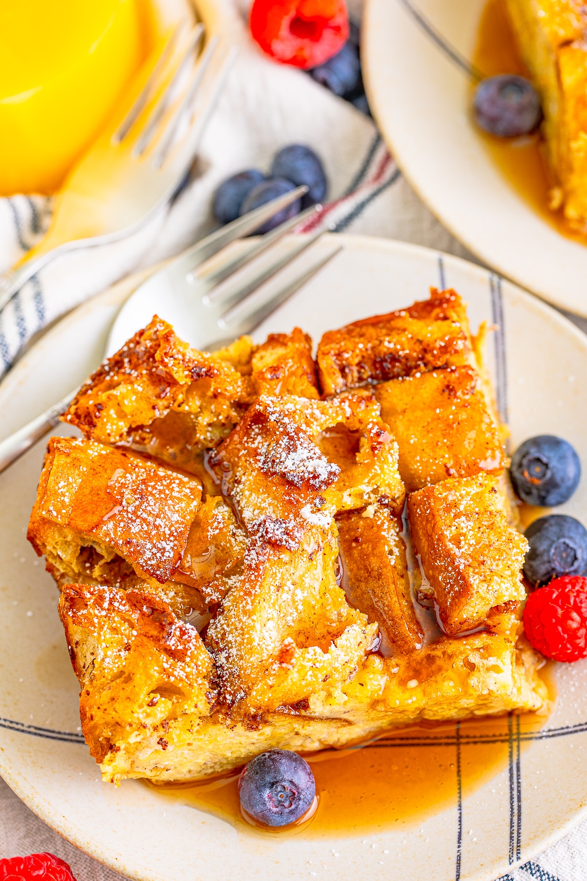 a slice of overnight french toast casserole on a tan plate with maple syrup