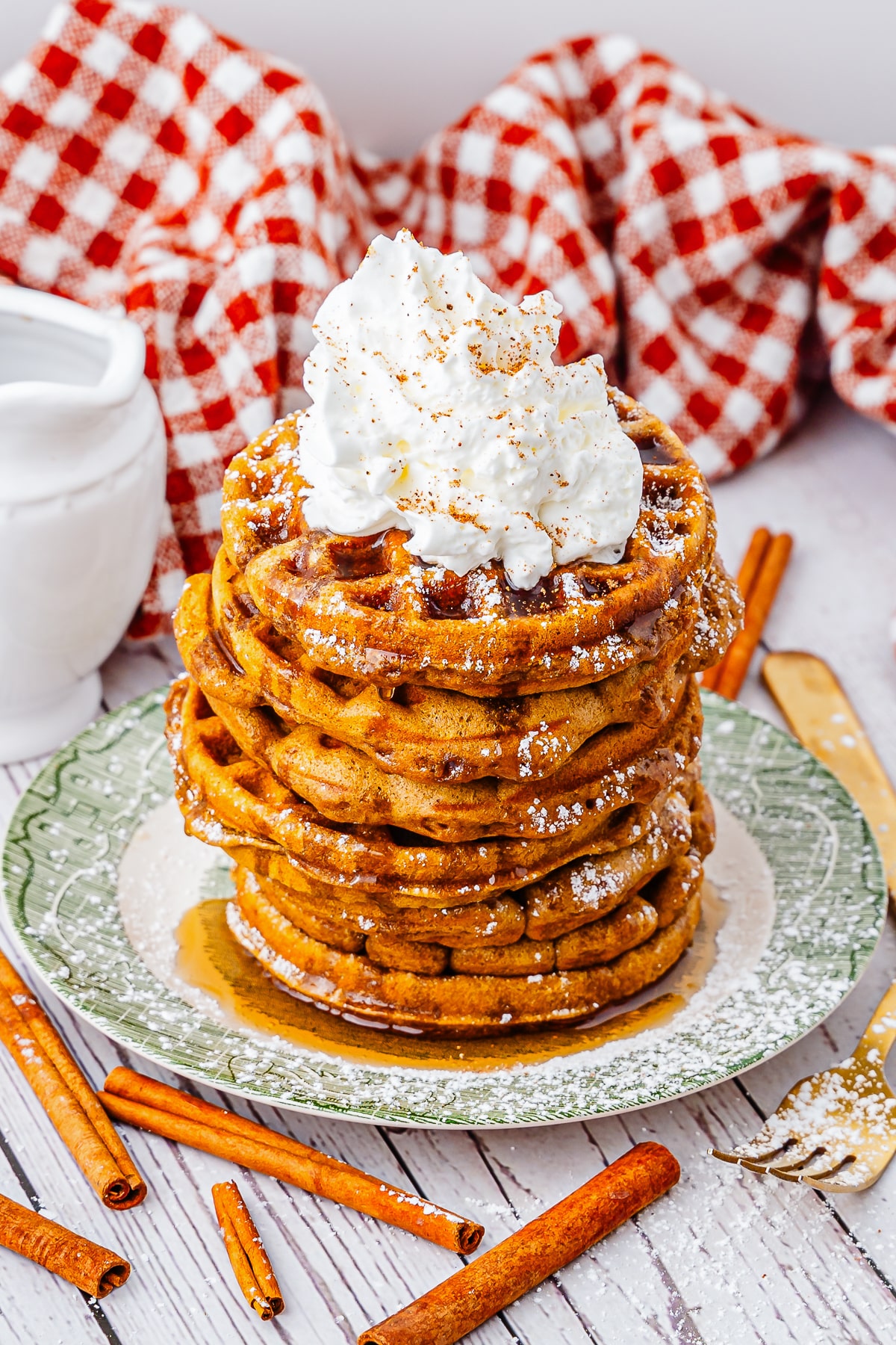 gingerbread waffles stacked on a green plate with whipped cream
