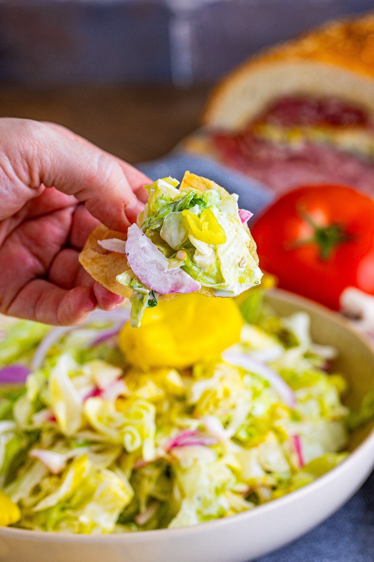 a hand holding up a scoop of salad for grinder sandwich recipe