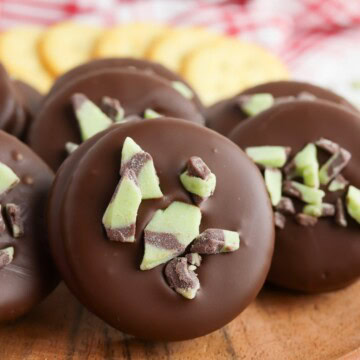 Chocolate covered Ritz crackers topped with chopped Andes mints stacked on a red and white checked towel.