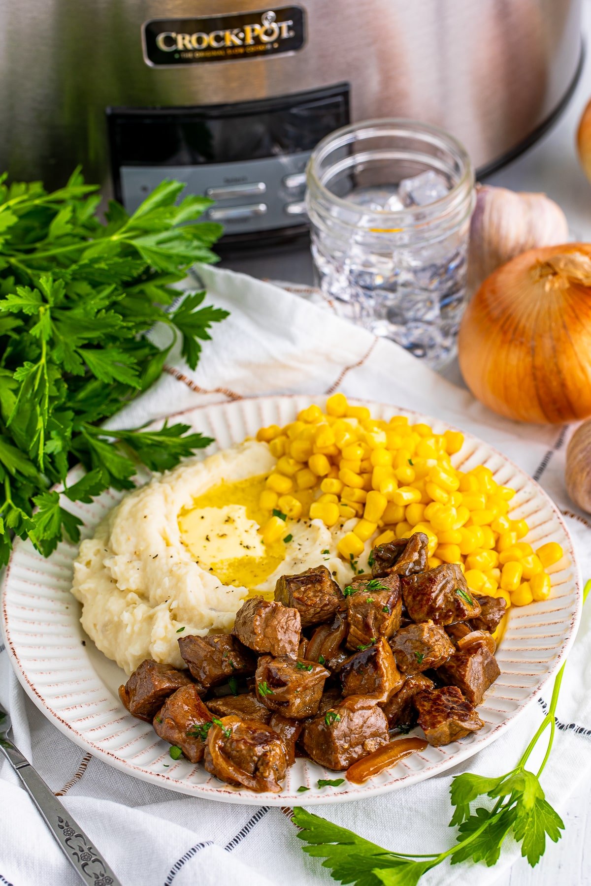 slow cooker steak bites on a tan plate with corn