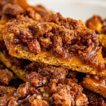 Stacked pieces of cinnamon sugar graham cracker toffee topped with candied pecans.