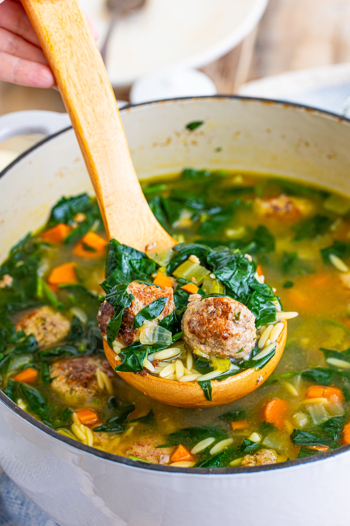 a ladel scooping out the best italian wedding soup recipe from a dutch oven