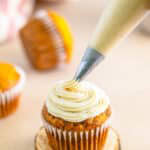 Cinnamon Cream Cheese Frosting being piped in a tall swirl onto a cupcake.