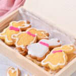 Decorated Easter bunny cookies with white glaze outlines and pink collars arranged in a wooden gift box.