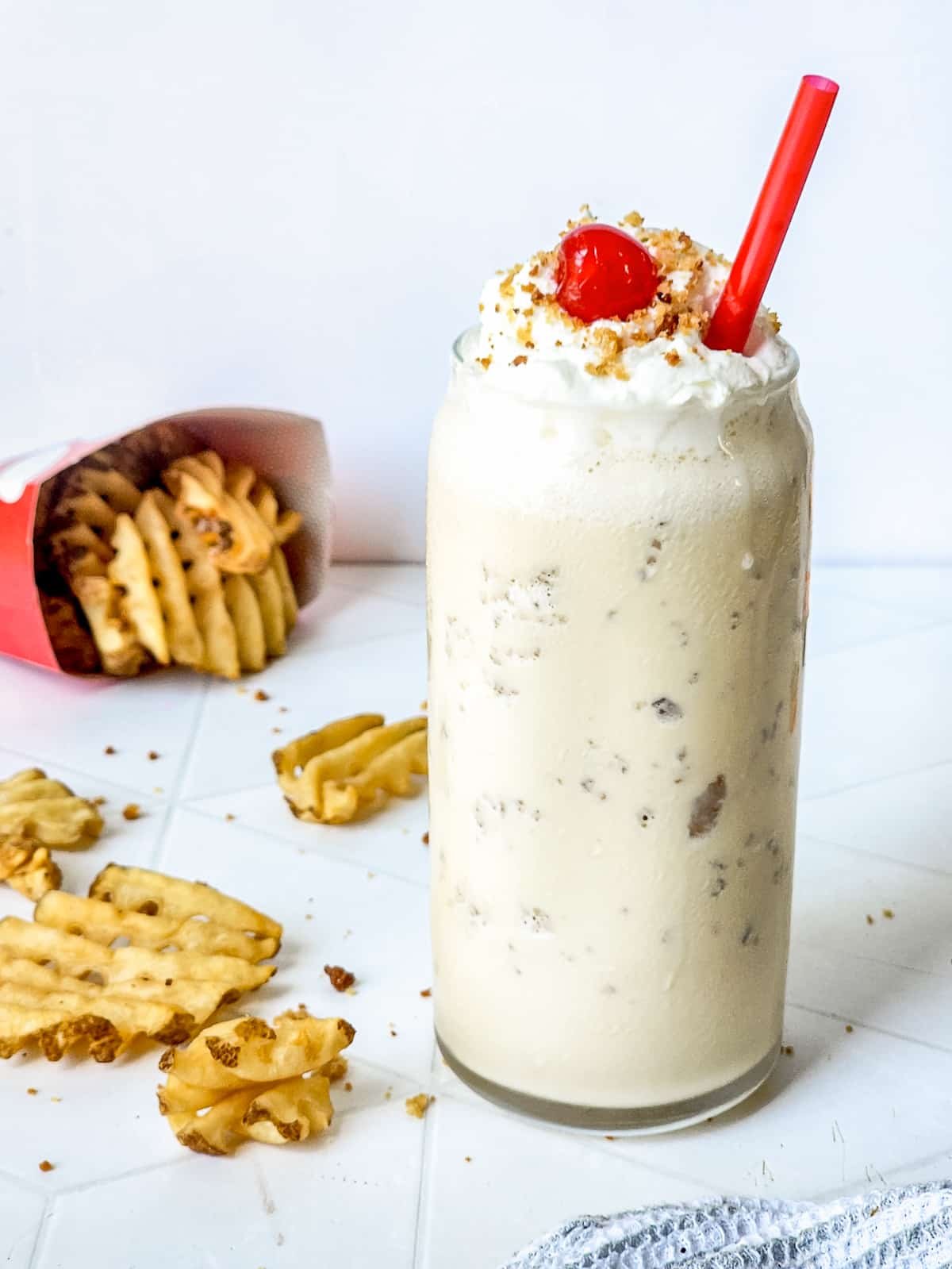 caramel milkshake in a tall glass with red straw