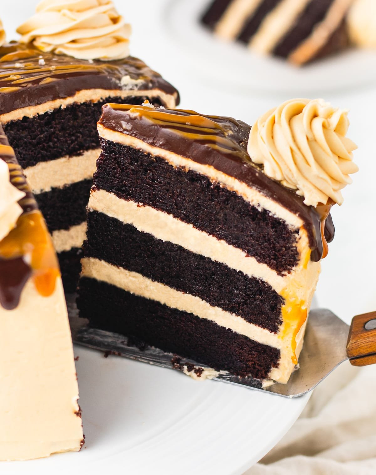 a cake server taking out a slice of chocolate caramel cake