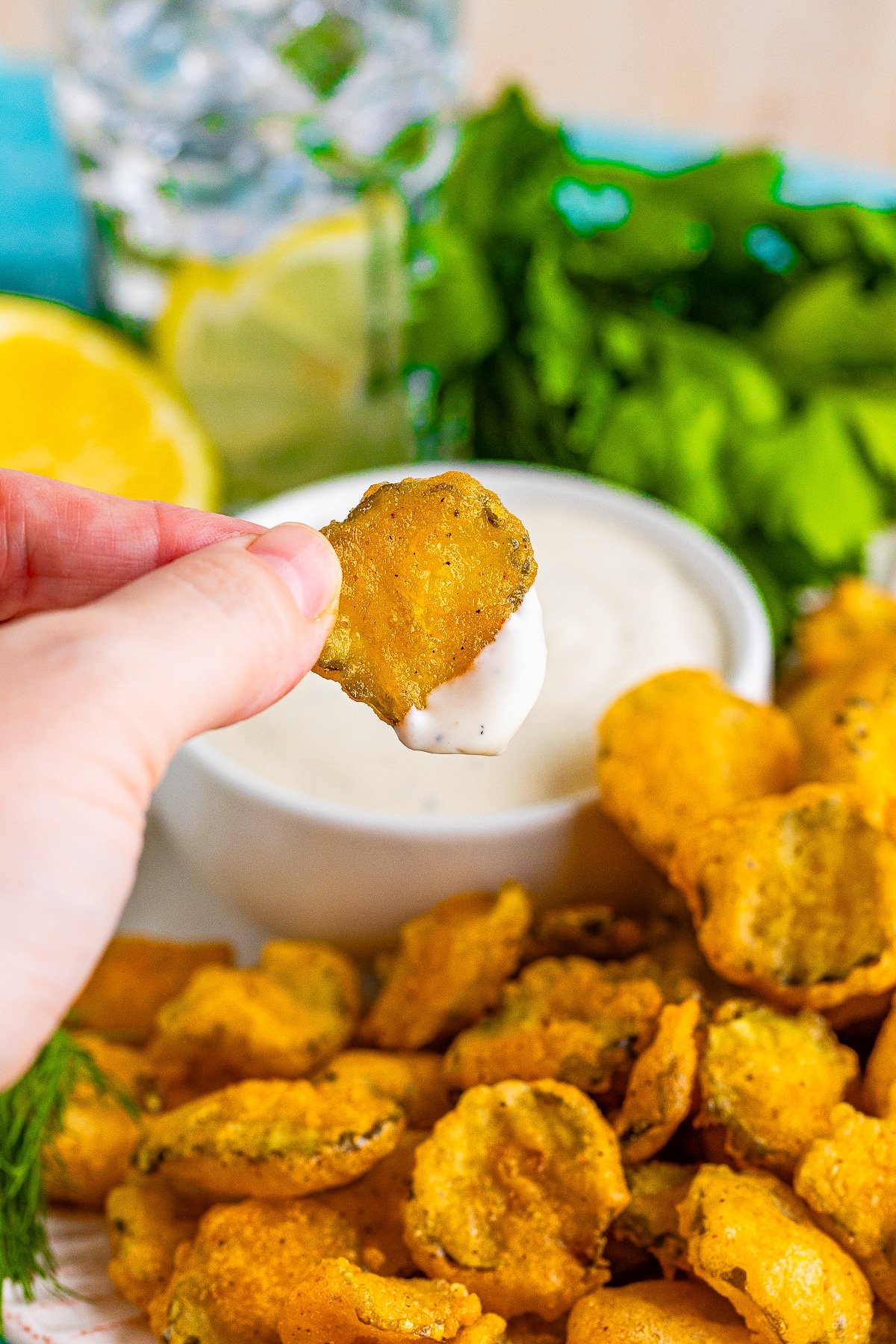 a hand holding up deep fried pickles recipe that has been dipped in ranch