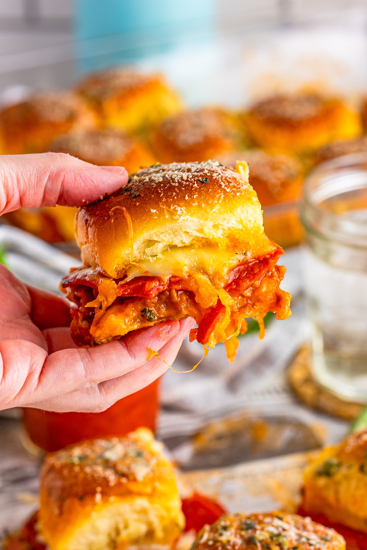 a hand holding up pizza sliders in air