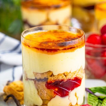 A mini trifle in a glass with torched creme brulee sugar top, layers of custard, shortbread, and raspberry jam.