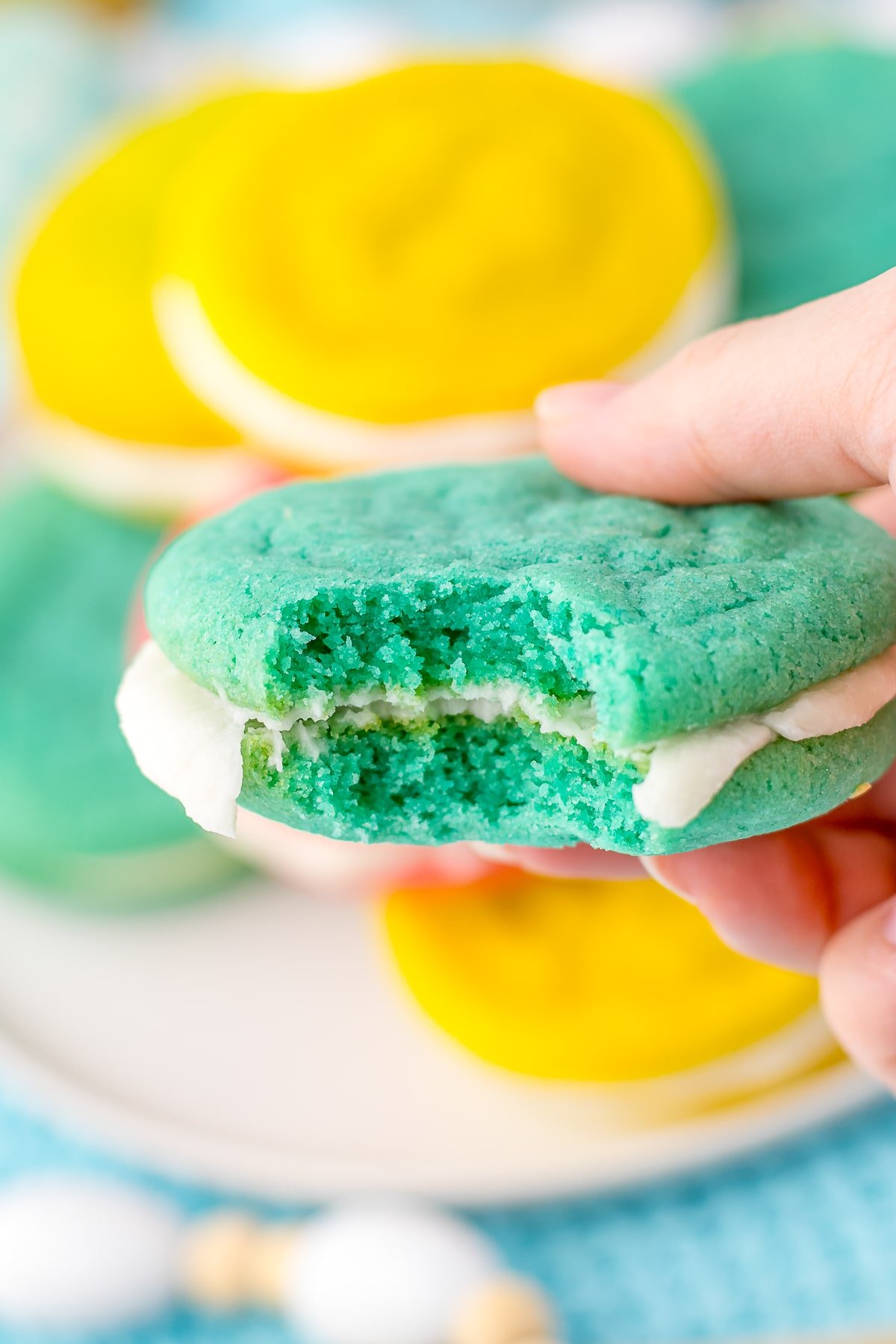a hand holding up easter sugar cookies with a bite taken out