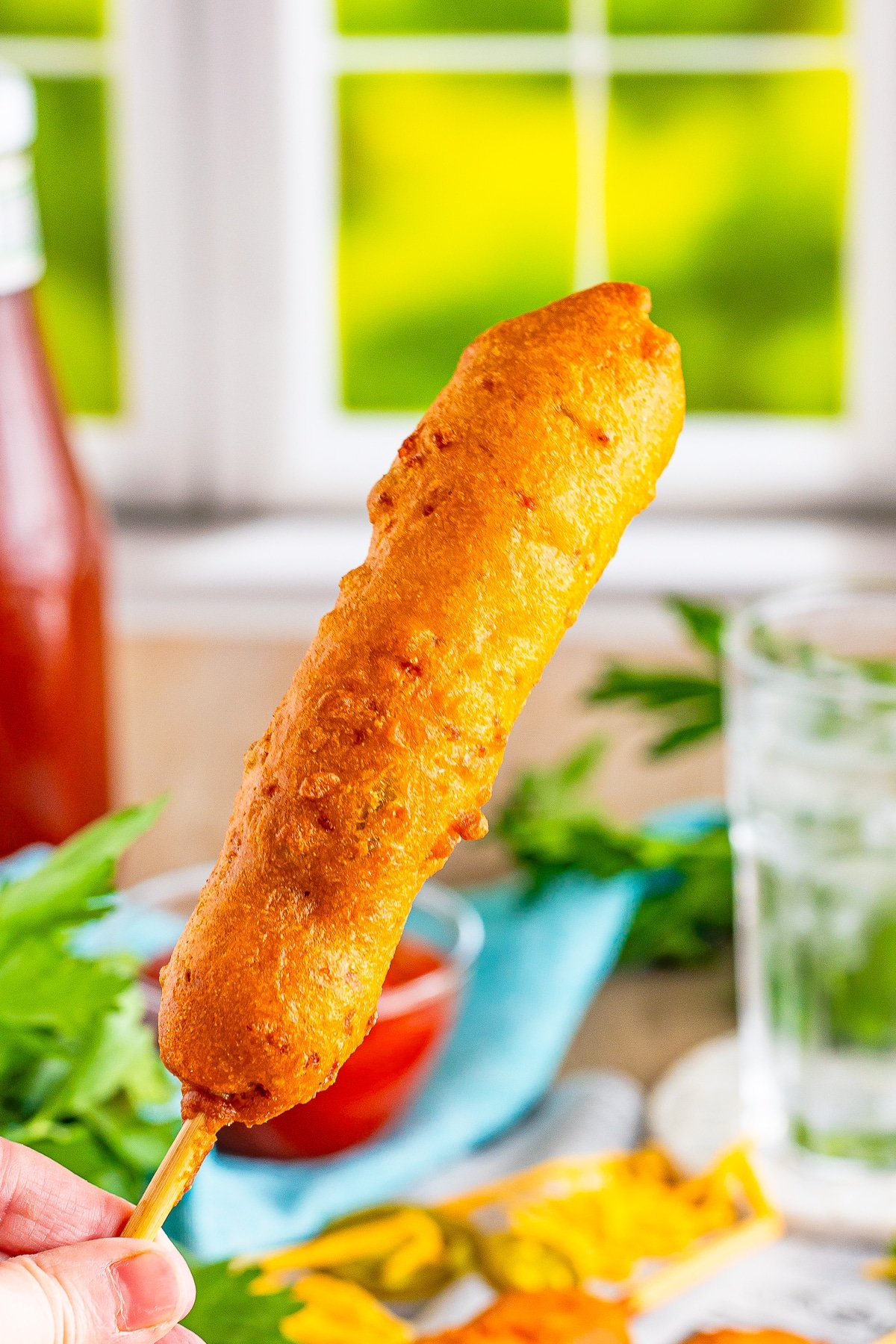 a hand holding up corn dogs recipe in air