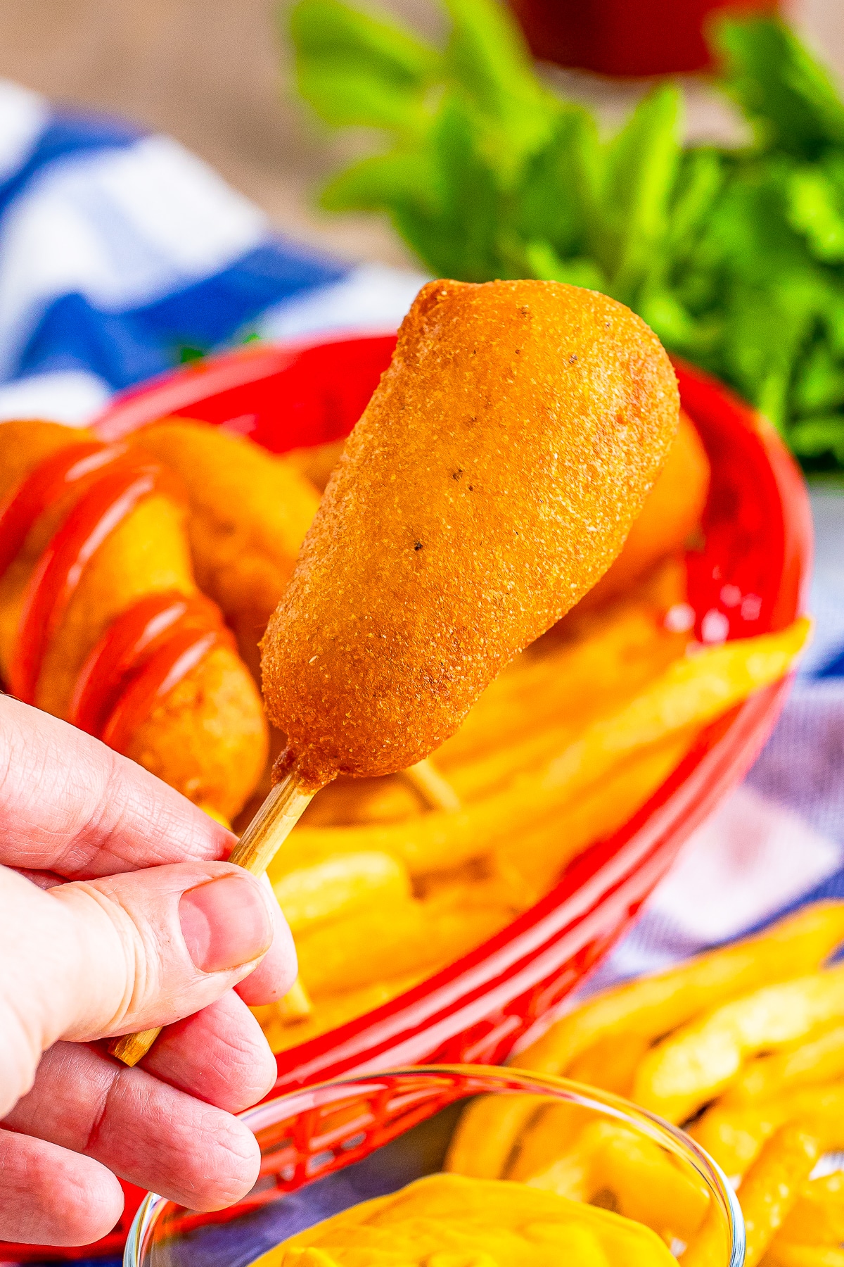 a hand holding up mini corn dogs in air