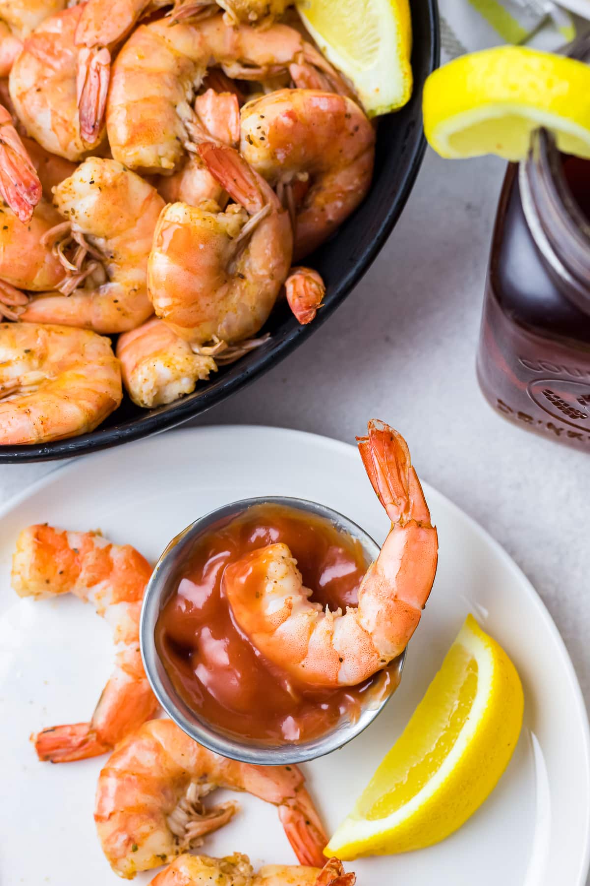 peel and eat shrimp on a white plate with a shrimp in cocktail sauce
