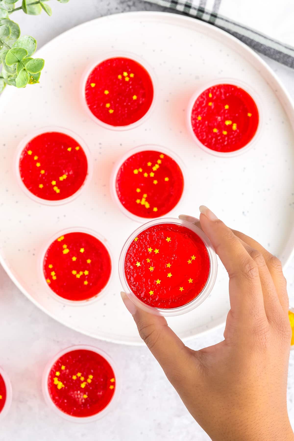 a hand holding up jello shots recipe in air