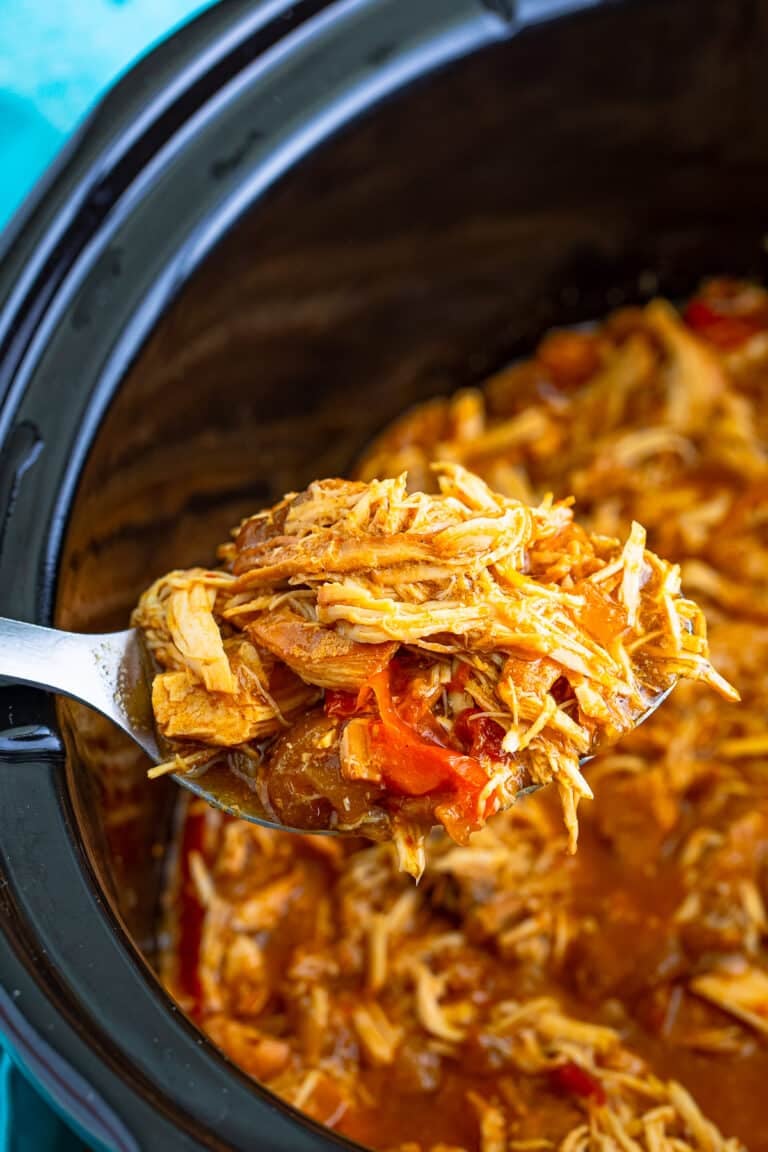 Slow cooker shredded chicken with peppers and onions in the pot, ready to serve.