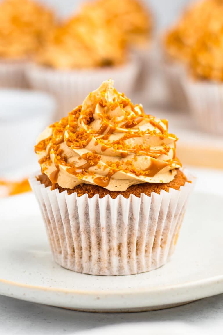 Biscoff cupcake with a tall cookie butter frosting swirl and Speculoos cookie crumbs on a white plate.