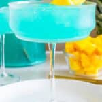 Blue Hawaiian Cocktail in a coupe glass garnished with fresh pineapple.
