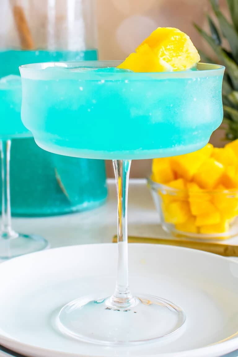 Blue Hawaiian Cocktail in a coupe glass garnished with fresh pineapple.