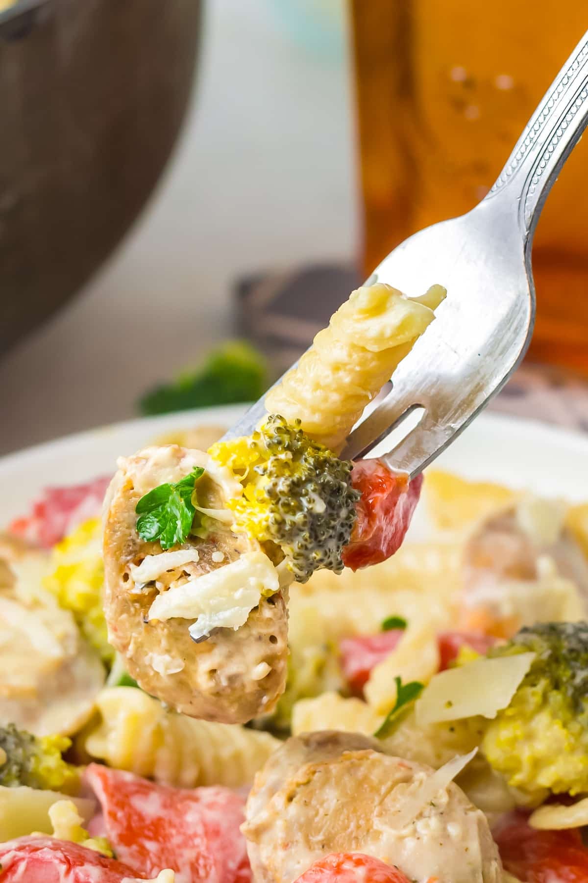 a fork holding up a bite of chicken sausage pasta dish in air
