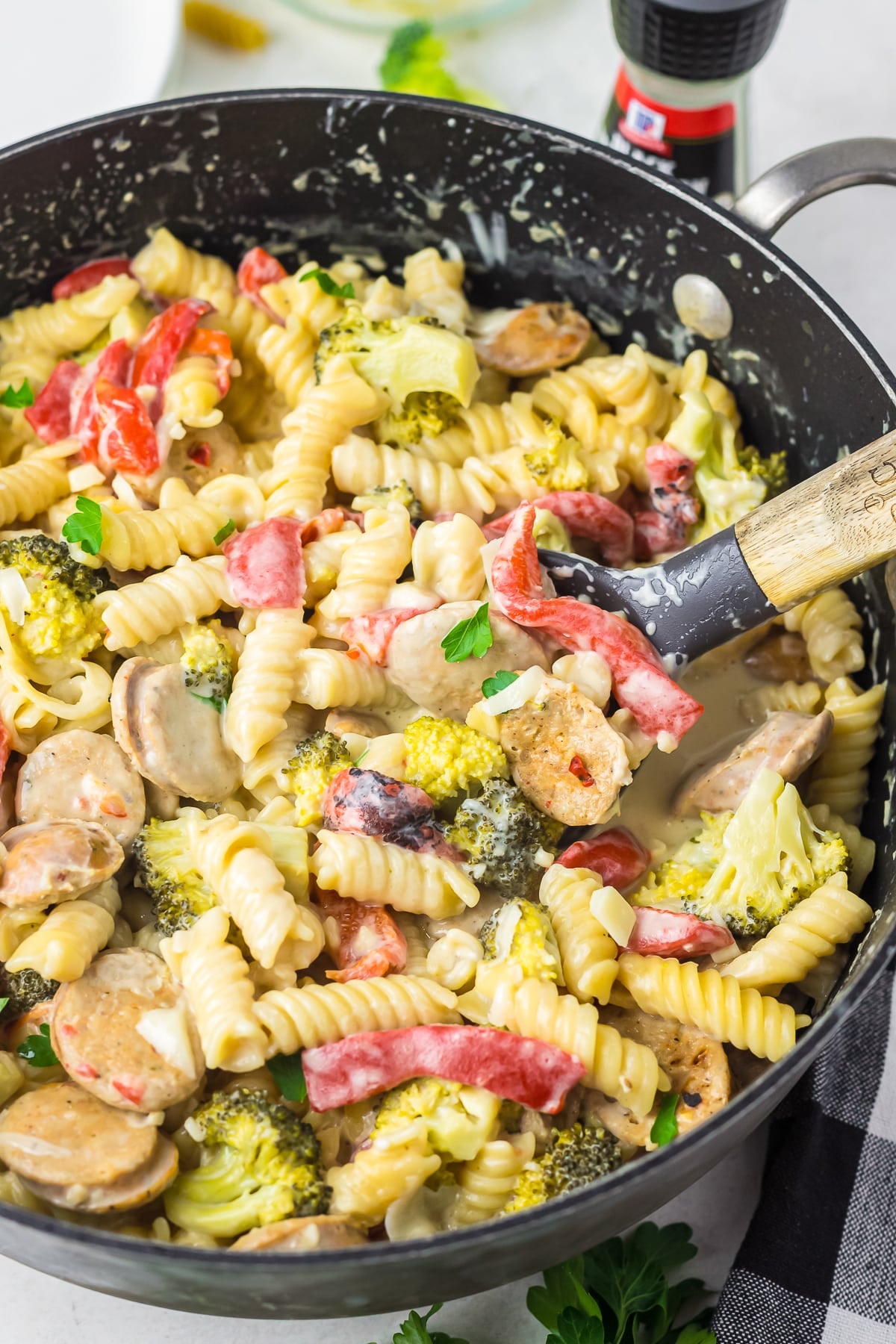 chicken sausage pasta dish in the skillet with a spoon scooping some out