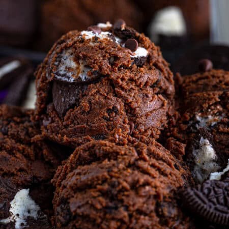 A bowl of edible chocolate cookie dough with Oreos and chocolate chips scooped into balls.