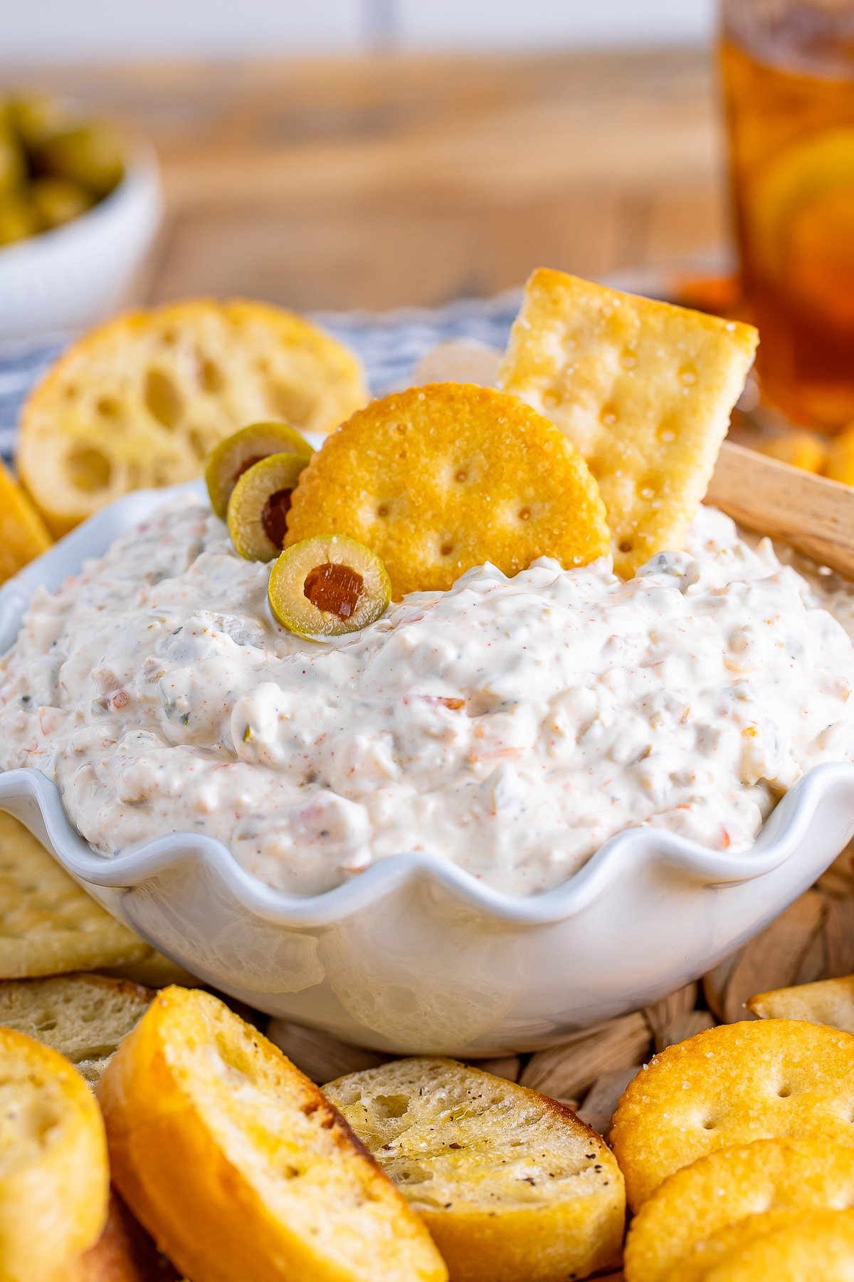 olive dip in serving bowl with crackers in it